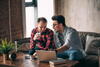 Male couple in apartment looking at computer while sitting on couch